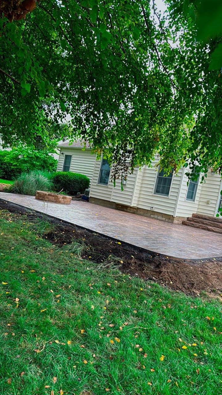 Stamped concrete patio with built-in fire pit under a shade tree